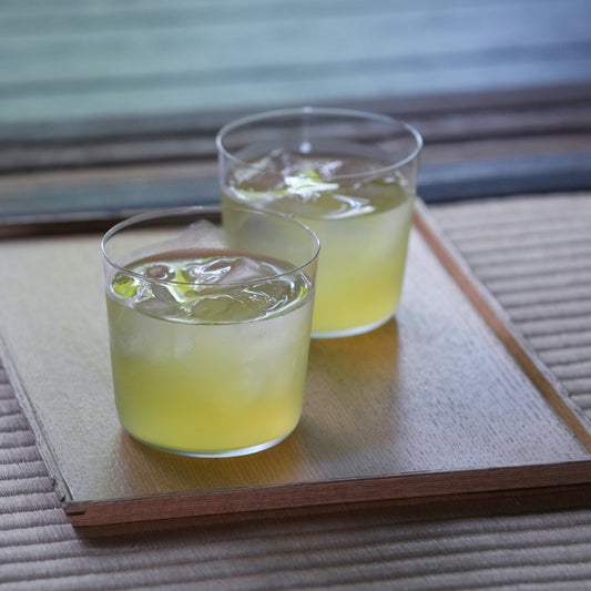 Glass of Nakamura Tokichi Cold Brew Green Tea with Ice and Condensation Drops on wood plate