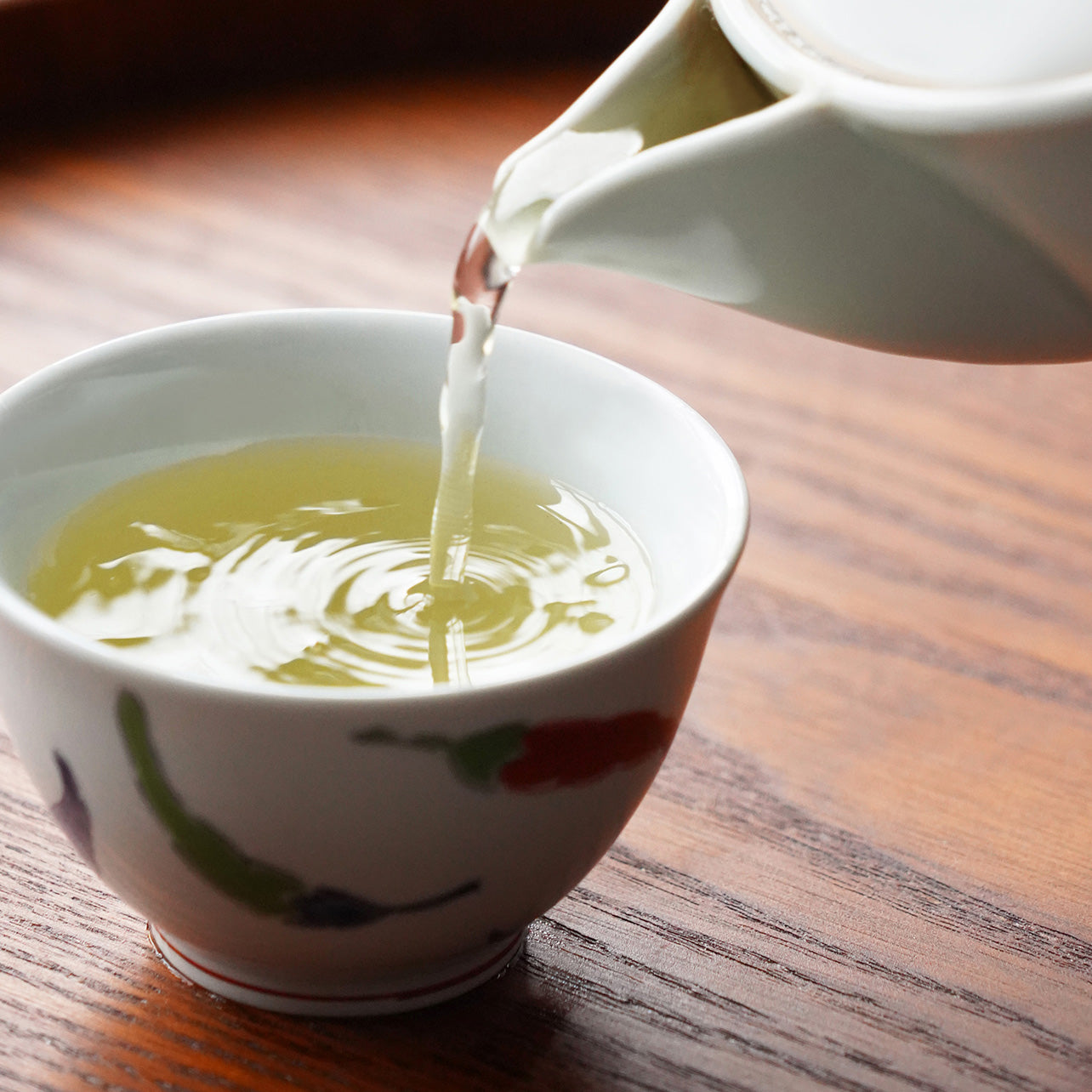 Nakamura Tokichi Sencha being poured from a teapot into teacups on a wood tray