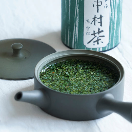 Nakamura Tokichi Signature Nakamura-cha loose leaf tea steeping in a modern teapot, with the iconic green tea tin canister in the background.