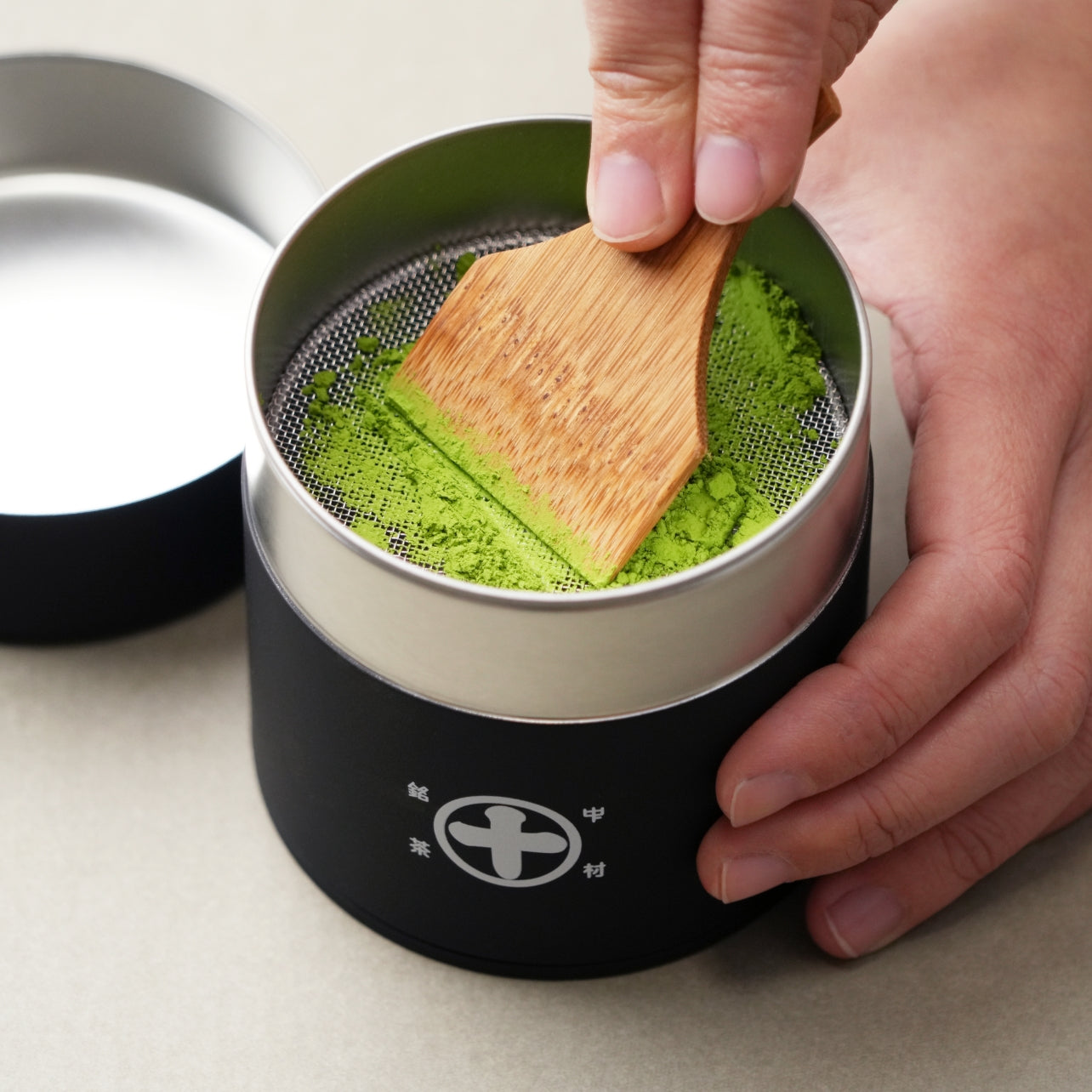 Using a Nakamura Tokichi Uji Maruto Matcha Sifter Tin and Takehera bamboo spatula to sift ceremonial grade matcha powder for a smooth texture.