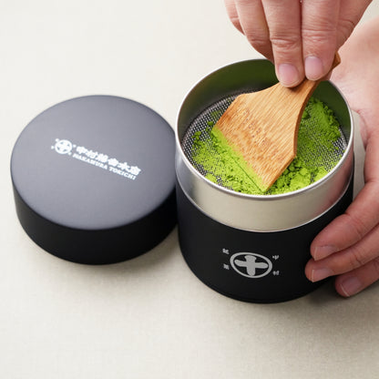 Using a Nakamura Tokichi Uji Maruto Matcha Sifter Tin and Takehera bamboo spatula to sift ceremonial grade matcha powder for a smooth texture.